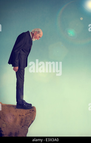 Senior uomo in piedi da solo su una scogliera battuta depressione concetto di suicidio Foto Stock