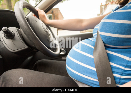 Una donna incinta che indossa la cintura di sicurezza guida un'auto.  Sicurezza e guida durante la gravidanza, il viaggio Foto stock - Alamy