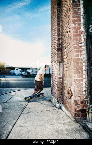 Uomo caucasico skateboard equitazione sulla strada di città Foto Stock