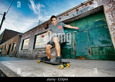 Uomo caucasico skateboard equitazione sulla strada di città Foto Stock