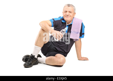 Active uomo maturo tenendo una bottiglia di acqua seduti a terra Foto Stock