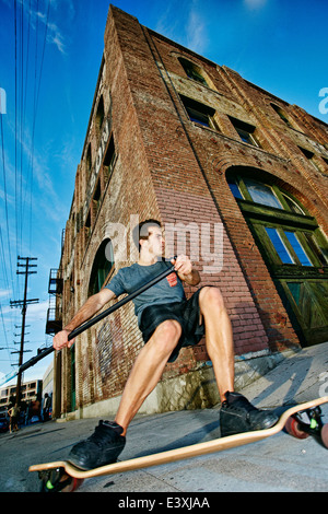 Uomo caucasico skateboard di equitazione con pala di terra Foto Stock