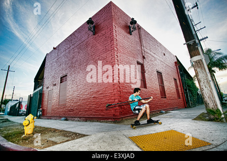 Uomo caucasico skateboard di equitazione con pala di terra Foto Stock