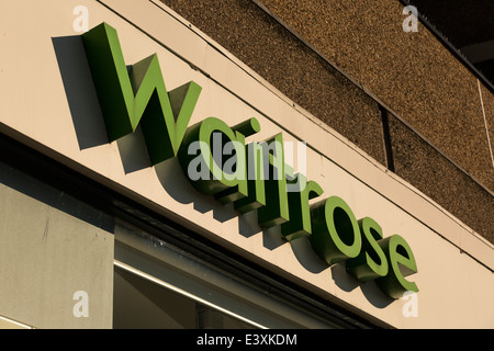 Close up slant vista della cartellonistica per Waitrose negozio di generi alimentari negozio di alimentari a Byres Road, Glasgow, Scotland, Regno Unito con inizio dalla luce del sole. Foto Stock