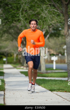 Uomo caucasico jogging sulla strada suburbana Foto Stock