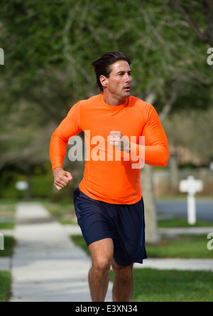 Uomo caucasico jogging sulla strada suburbana Foto Stock