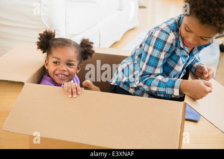 Il nero dei bambini che giocano in una scatola di cartone Foto Stock