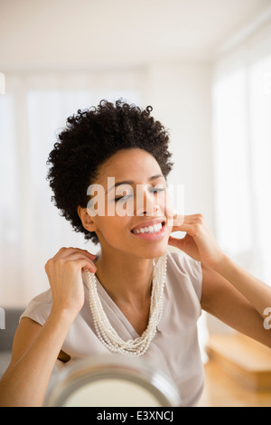 Nero donna cercando su collana in specchio Foto Stock