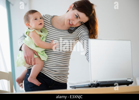 Il multitasking madre con bambino Foto Stock