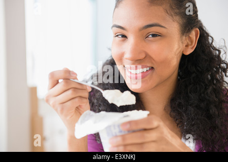 Razza mista donna mangiare yogurt Foto Stock