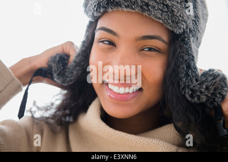 Razza mista donna che indossa un peloso hat nella neve Foto Stock