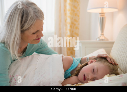 Senior donna caucasica mettendo la nipote a letto Foto Stock