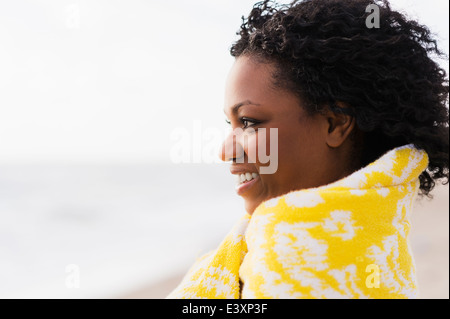 African American donna avvolta in asciugamano sulla spiaggia Foto Stock