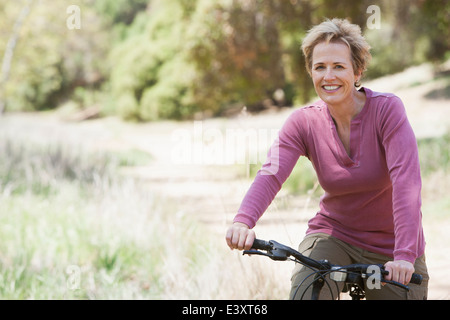 Senior donna caucasica equitazione Bicicletta sul percorso rurale Foto Stock