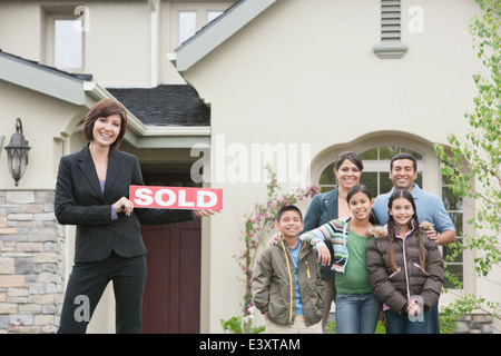 Agente immobiliare e la famiglia sorridente al di fuori di nuovo home Foto Stock