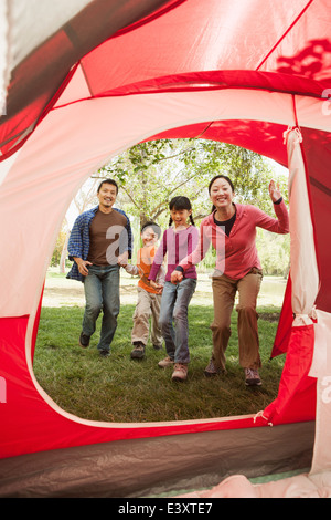 Famiglia in esecuzione per la tenda al campeggio Foto Stock