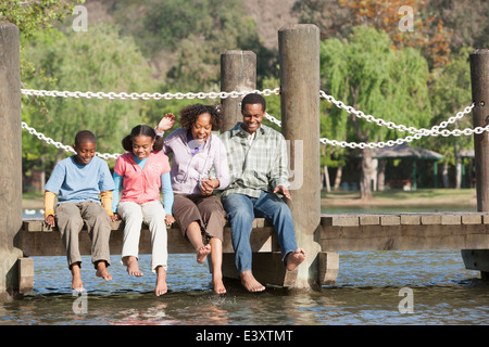 Famiglia seduta sul dock di legno nel lago Foto Stock