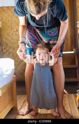 Madre caucasica aiutando baby stand Foto Stock