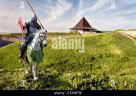 Il cavaliere corazzato su warhorse sopra il vecchio castello medievale (fortezza) Foto Stock