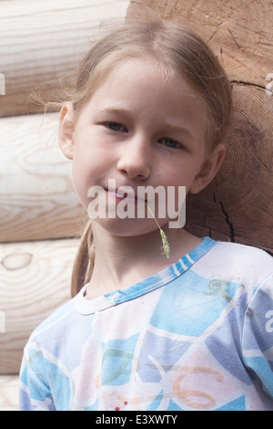 Ritratto di piccola ragazza caucasica su tronchi di legno sfondo a parete Foto Stock