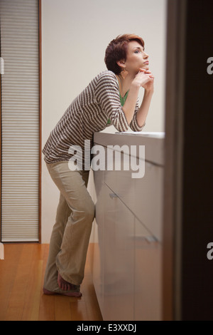 Donna appoggiata sul banco di cucina Foto Stock