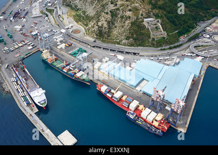 VISTA AEREA. Navi portacontainer a fianco delle banchine di carico nel porto commerciale di Savona. Begeggi, Provincia di Savona, Liguria, Italia. Foto Stock