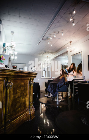 La stilista spazzolare i capelli dei clienti in salone Foto Stock