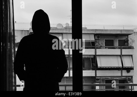 Uomo che guarda alla città vista attraverso il vetro silhouette astratta. In bianco e nero. Foto Stock