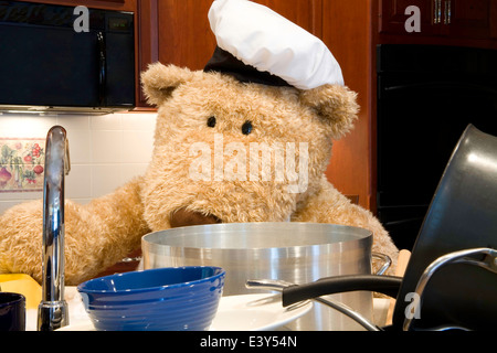 Oversized orsacchiotto di peluche vestito di chef's grembiule e cappello in cucina. Foto Stock