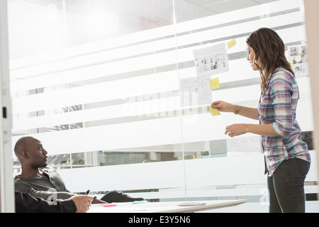 Giovane imprenditrice presentare idee ai colleghi di sesso maschile Foto Stock