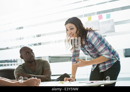 Imprenditrice spiegando le idee ai colleghi di sesso maschile in office Foto Stock