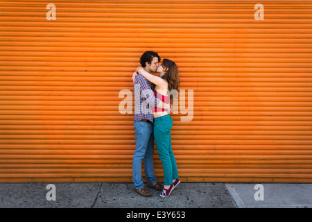 Coppia romantica baciare davanti a otturatore arancione Foto Stock