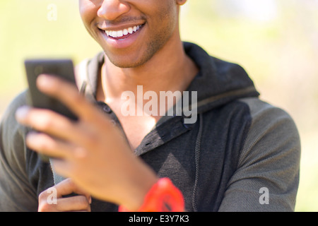 Chiusura del giovane maschio escursionista guardando smartphone Foto Stock