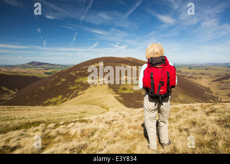 Una donna hill walker guardando verso Scawdmans collina sopra Biggar negli altipiani del Sud della Scozia, Regno Unito Foto Stock