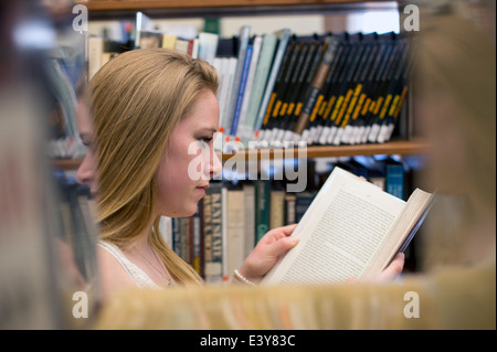 Giovane donna libro di lettura in biblioteca Foto Stock