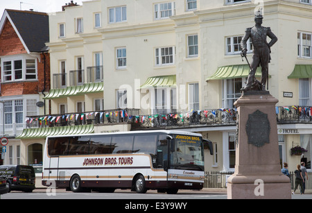 Inglese resorts Holiday autobus fuori dall'hotel e il Royal Sussex Regimental statua 1920 su Marine Parade, Eastbourne East Sussex Foto Stock