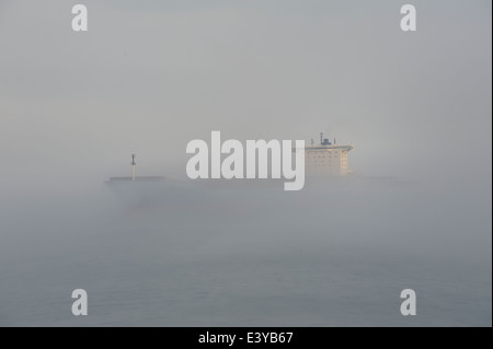 Nave da carico contemplati nella nebbia di mare Foto Stock