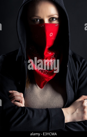 Su uno sfondo nero ragazza forma formidabile nella cappa nera con uno scialle rosso sul suo volto Foto Stock