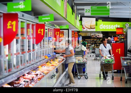 Gli acquirenti che cercano occasioni nella corsia dei congelatori da 1 euro del supermercato ASDA Foto Stock