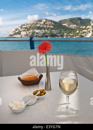 Tavolo da ristorante spagnolo all'aperto con pane fresco aglio, olive maionese e un bicchiere di vino bianco a Puerto Andratx Mallorca Baleari Spagna Foto Stock