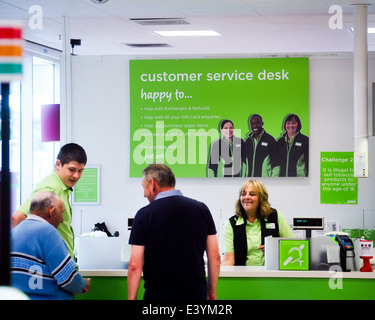 Il vecchio uomo di essere aiutato a un banco del servizio clienti nel supermercato Asda Foto Stock