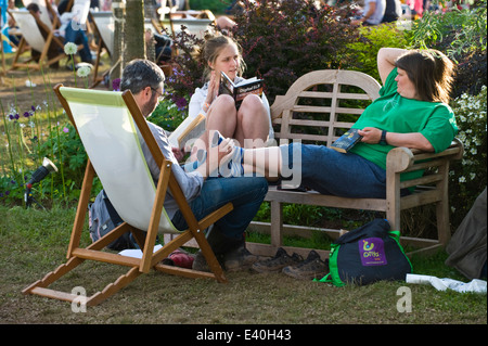 Un gruppo di 3 persone rilassante seduta sul banco e sdraio all'aperto a Hay Festival 2014 ©Jeff Morgan Foto Stock