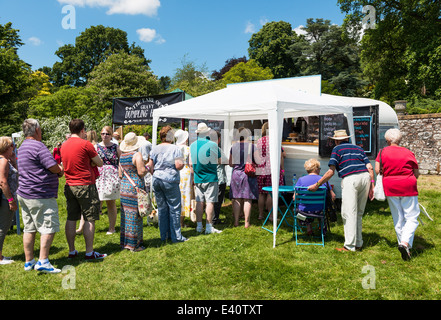 East Devon, in Inghilterra. Un Fete e party in giardino con una coda di persone in attesa di essere serviti spuntini e bevande in un caldo giorno d'estate. Foto Stock