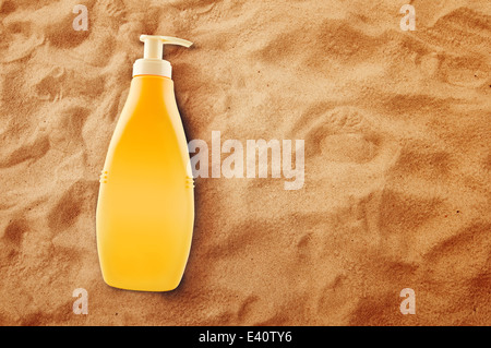 Bottiglia di olio di prendere il sole o la protezione solare caldo sulla spiaggia di sabbia in estate. Foto Stock