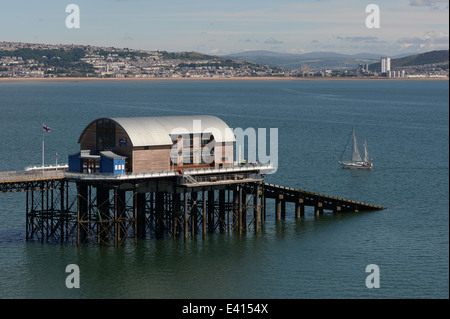 Vele yacht passati mumbles scialuppa di salvataggio sulla stazione alla fine del molo con Swansea City in background Foto Stock