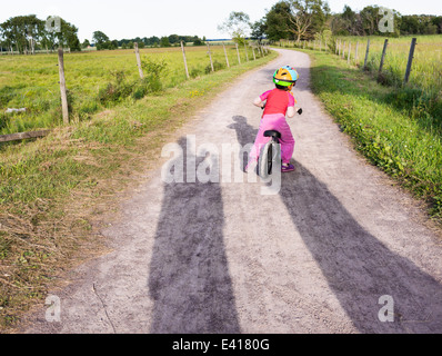 Tranquillo paesaggio estivo. Bambina in sella a una moto su una strada rurale in Svezia. Foto Stock