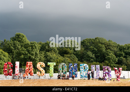 GLASTONBURY, Regno Unito - 28 giugno: i frequentatori del Festival guarda un panorama sul festival con un grande segno di Glastonbury Foto Stock