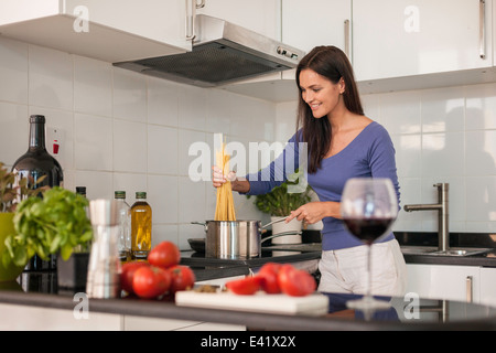 Giovane donna cucinare gli spaghetti in cucina Foto Stock