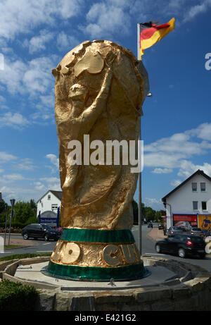 Salzkotten, Germania. 2 Luglio, 2014. Una replica della Coppa del mondo trofeo si erge nel mezzo di una rotatoria in Salzkotten, Germania, 02 luglio 2014. Il trofeo, che è di cinque meteres alta e pesa 400 chili, è stata fatta da un club locale. Il trofeo realizzato in fibra di vetro rinforzata con materiale sintetico era già stato installato durante la Coppa del Mondo 2010. Foto: Bernd Thissen/dpa/Alamy Live News Foto Stock