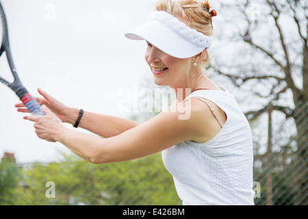 Femmina matura giocatore di tennis giocando a tennis Foto Stock